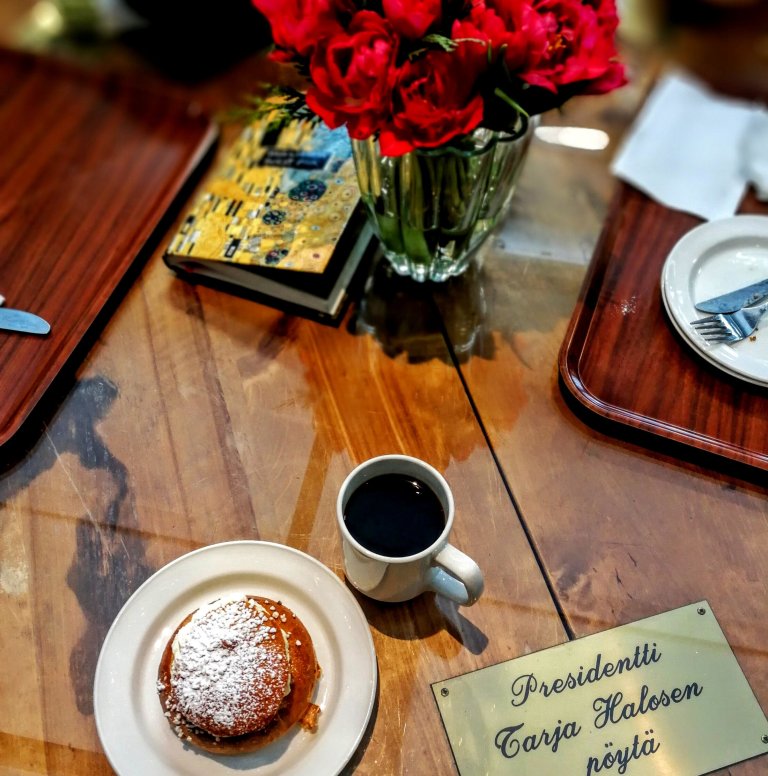 Hallikahvilassa nautitaan sumpit ja pullat letkeen arvokkaasti. Samassa pöydässä Espoosta hallia metrolla ihmettellemään tulleen eläkeläispariskunnan kanssa tuumattiin, pitääkö siirtyä toisaalle, jos nimikkopöydän henkilö saapuu